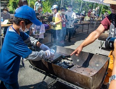 参加者らが松ぼっくりや木の枝を詰めたスチール缶を炭火に投入