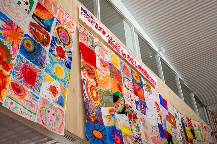思い思いの太陽の絵128点を集めてつなぎ合わせた大きな共同アート作品