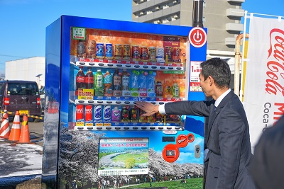桜並木などの写真でラッピングされた自販機