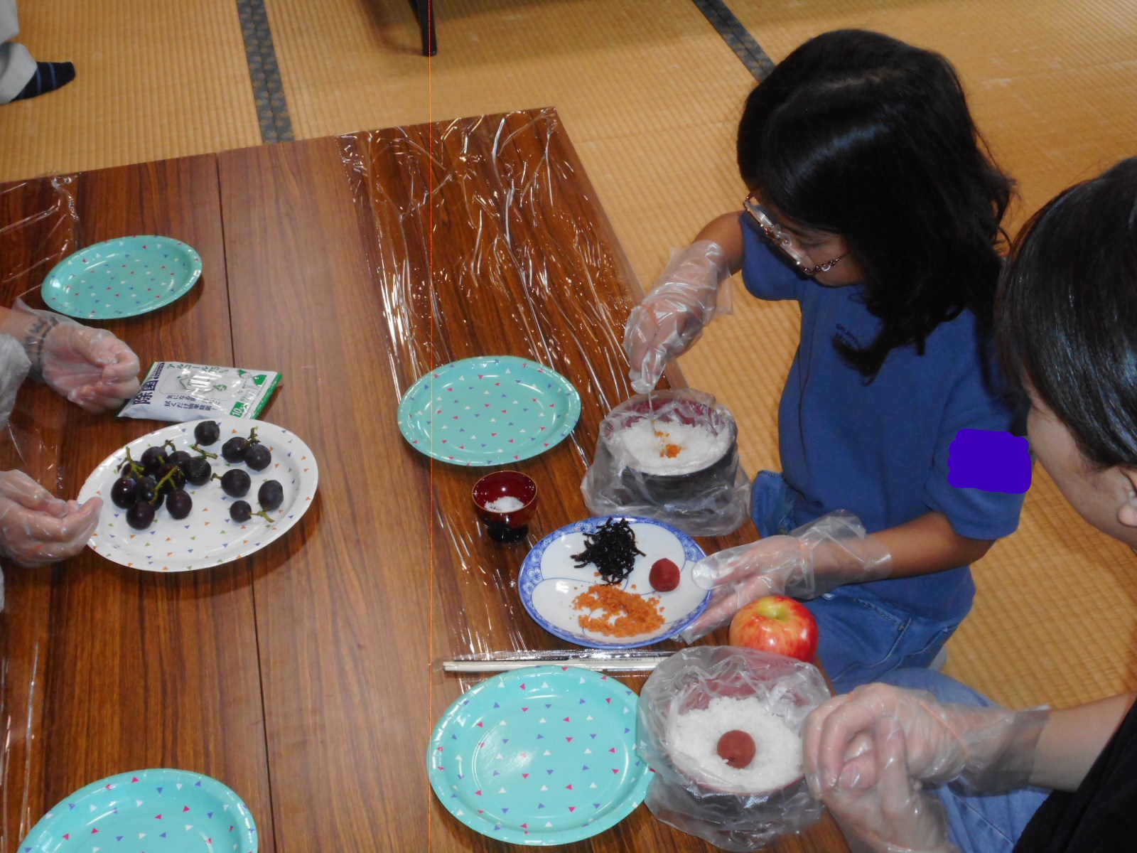 おにぎりの具をご飯に入れている子どもの写真